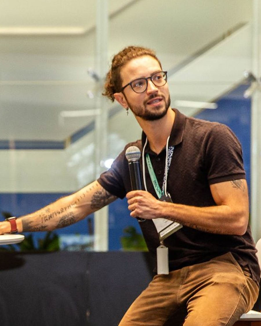 Matheus Kemer, fundador do Instituto Triângulo Tech, com microfone na mão durante uma apresentação.